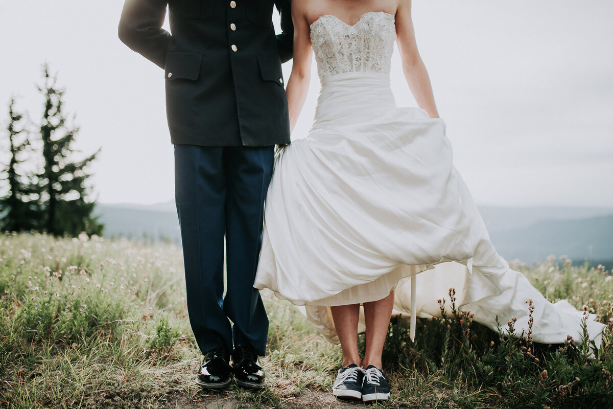Bride holding up her dress showing her sneakers next to the groom