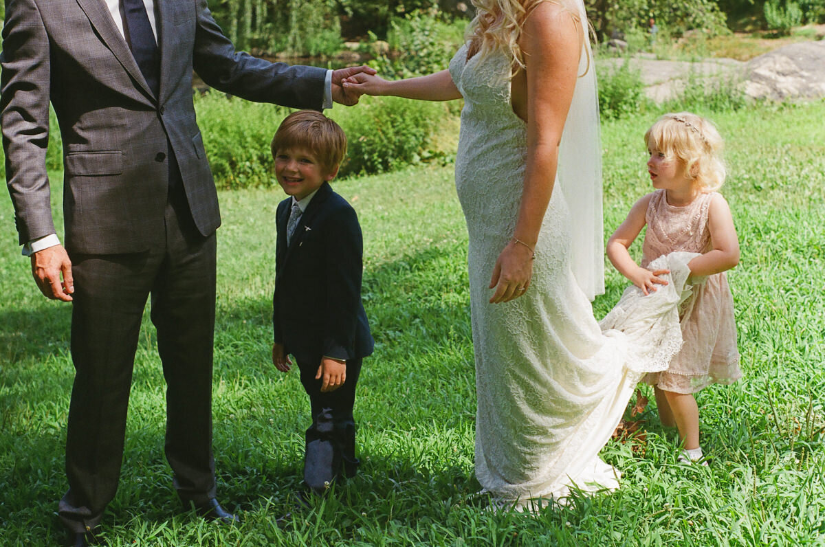 Two small children walking with a wedding couple.