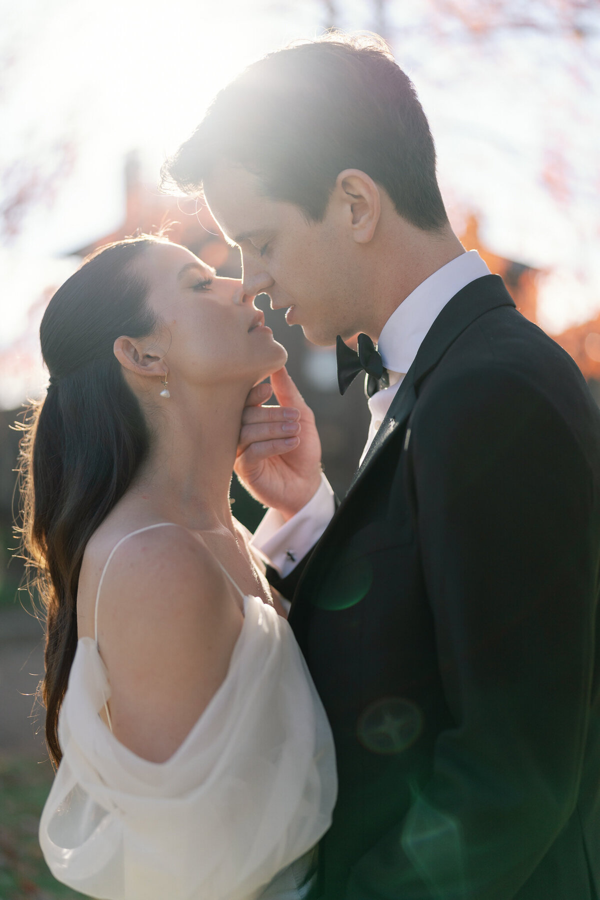 Groom gently touching bride's face at golden hour before a kiss
