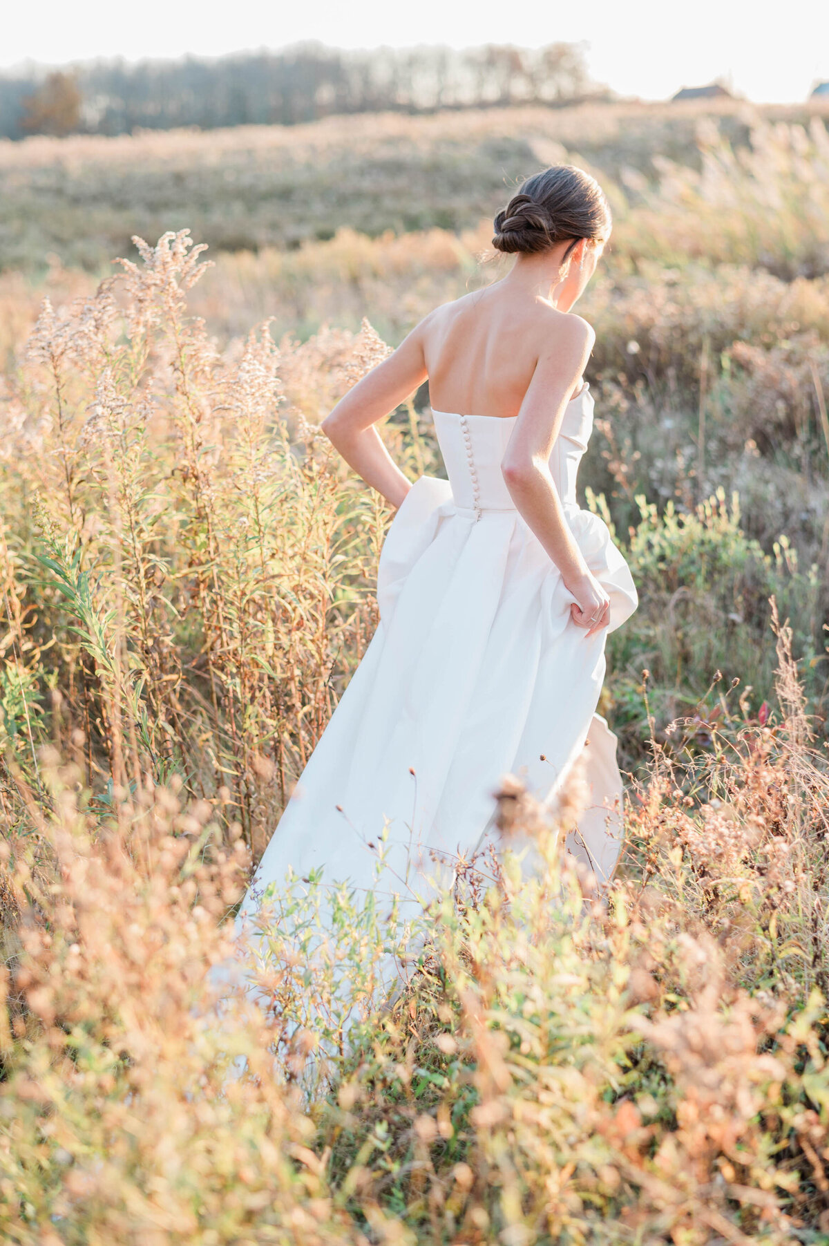 The bride gracefully walks alone through the meadow