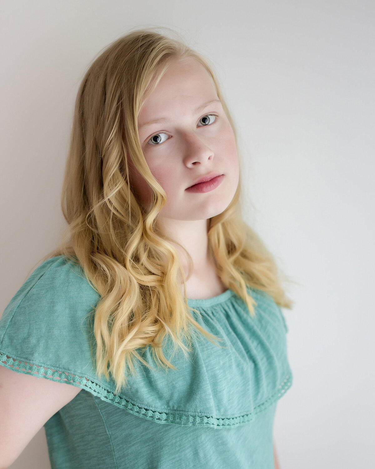 Female child actor headshot  wearing a light green shirt with a serious expression