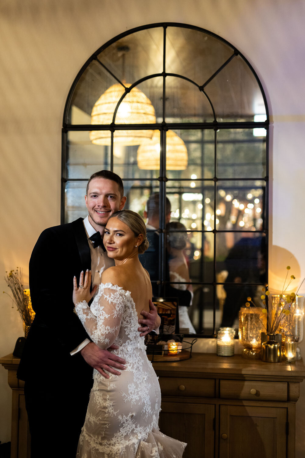 A bride and groom are posing for a picture in front of a window.
