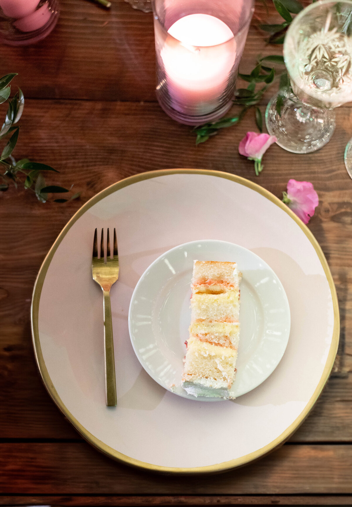 a wooden table with a pink plate and a cake