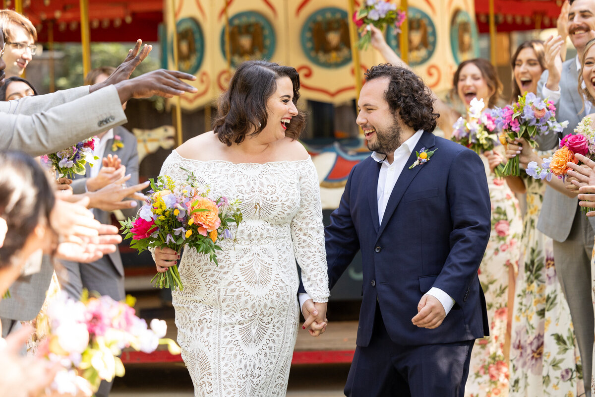 A bride and groom smiling at each other with their wedding parties around them