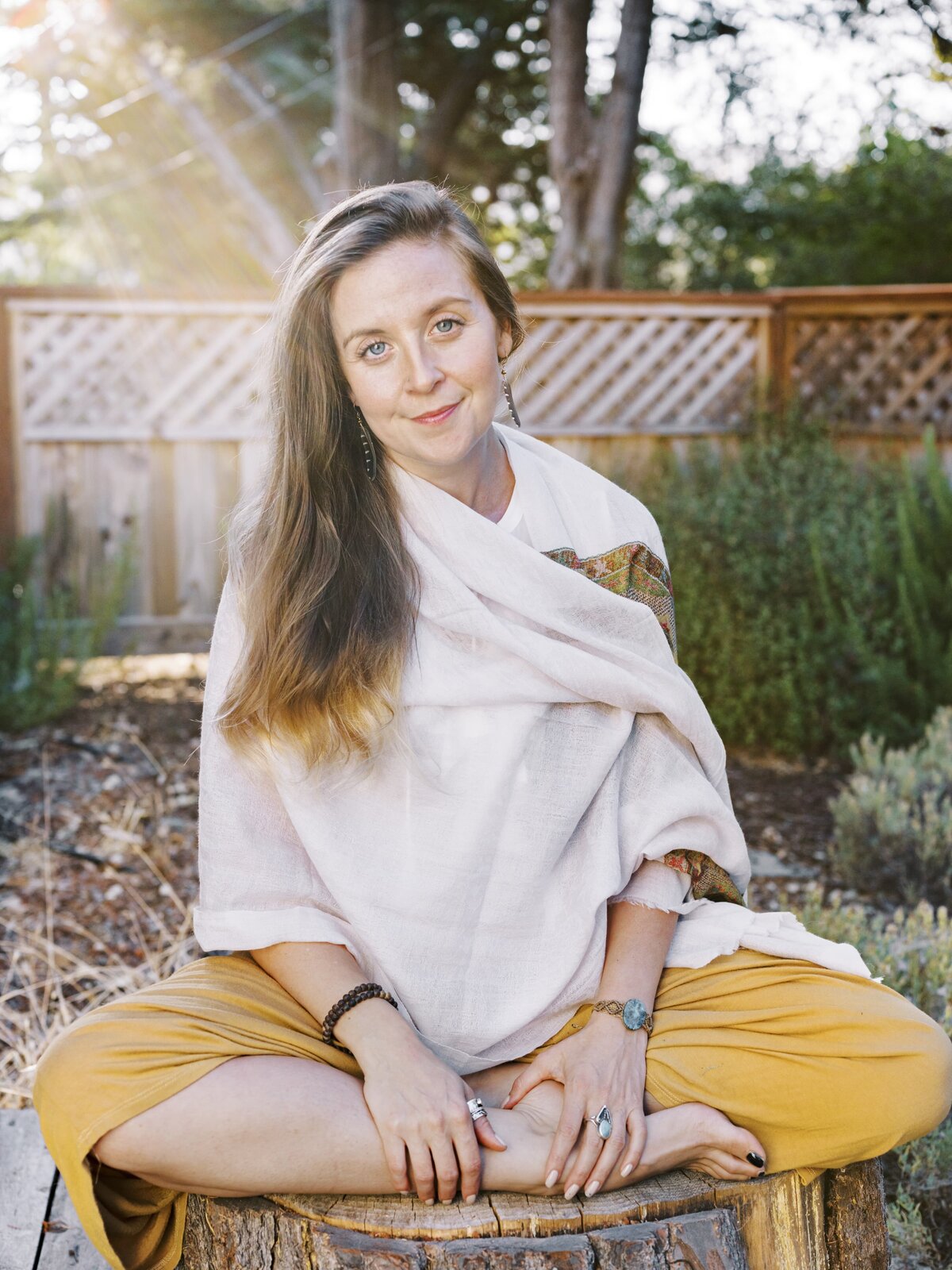 Woman sitting outside smiling with the sun streaming in