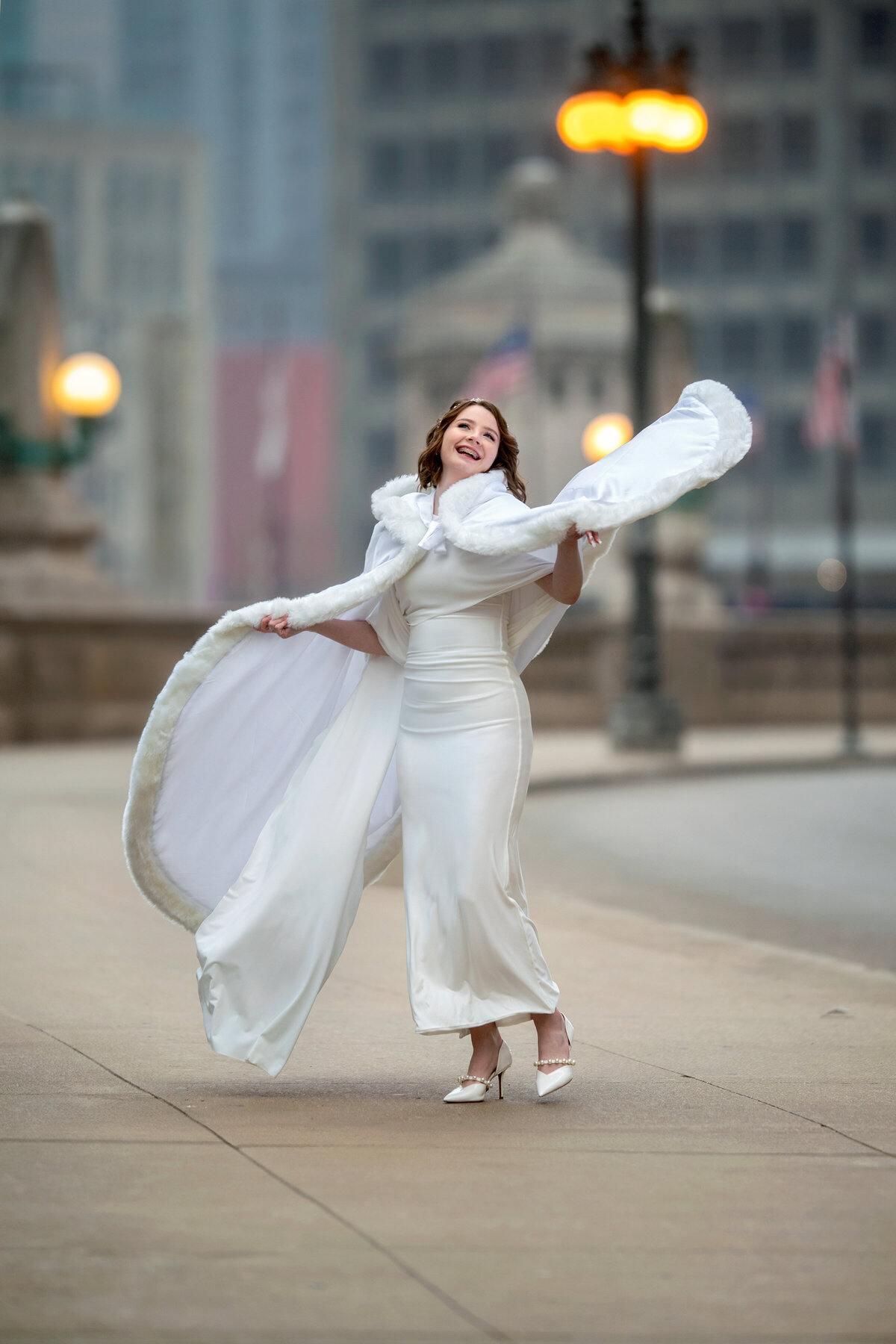 candid shot of bride wearing a cape dancing in the street of Chicago in the winter