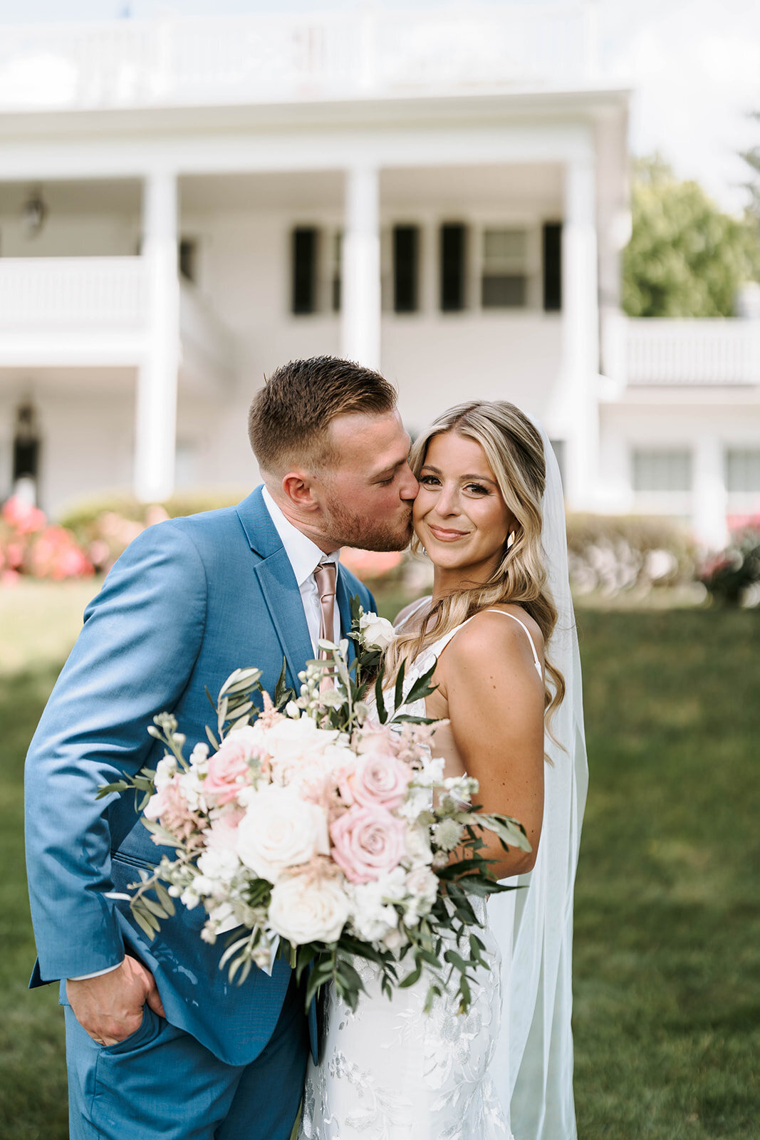 groom kissing brides cheek during outdoor portraits