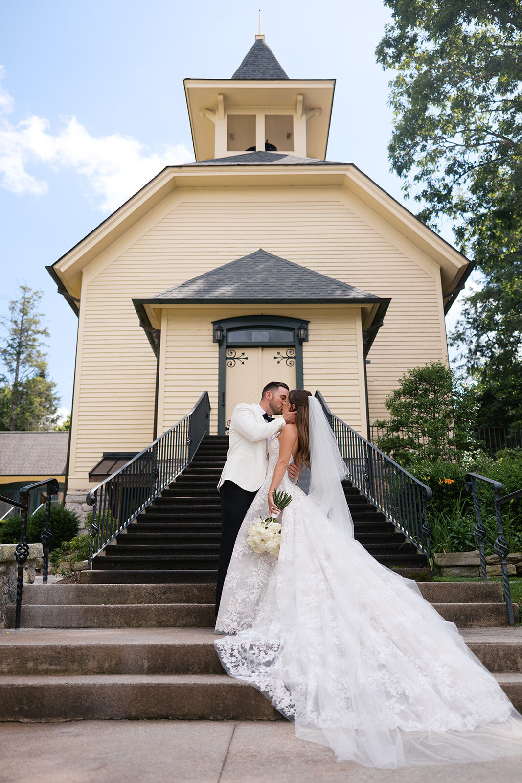 Bride and groom kissing on the steps of Our Lady of the Mountains Catholic Church in Highlands, NC.
