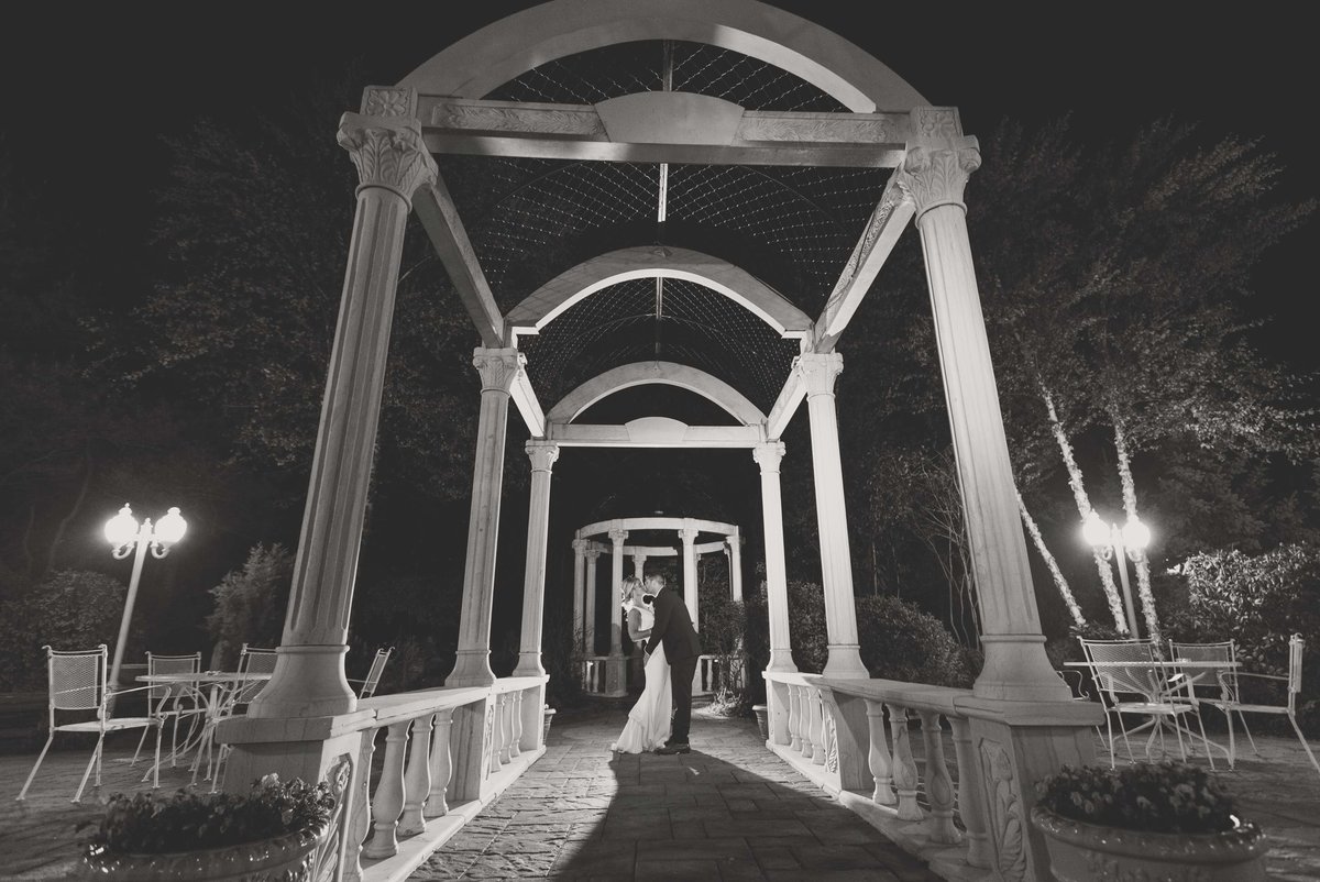 Black and white photo of the bride and groom kissing outside of Giorgio's Baiting Hollow