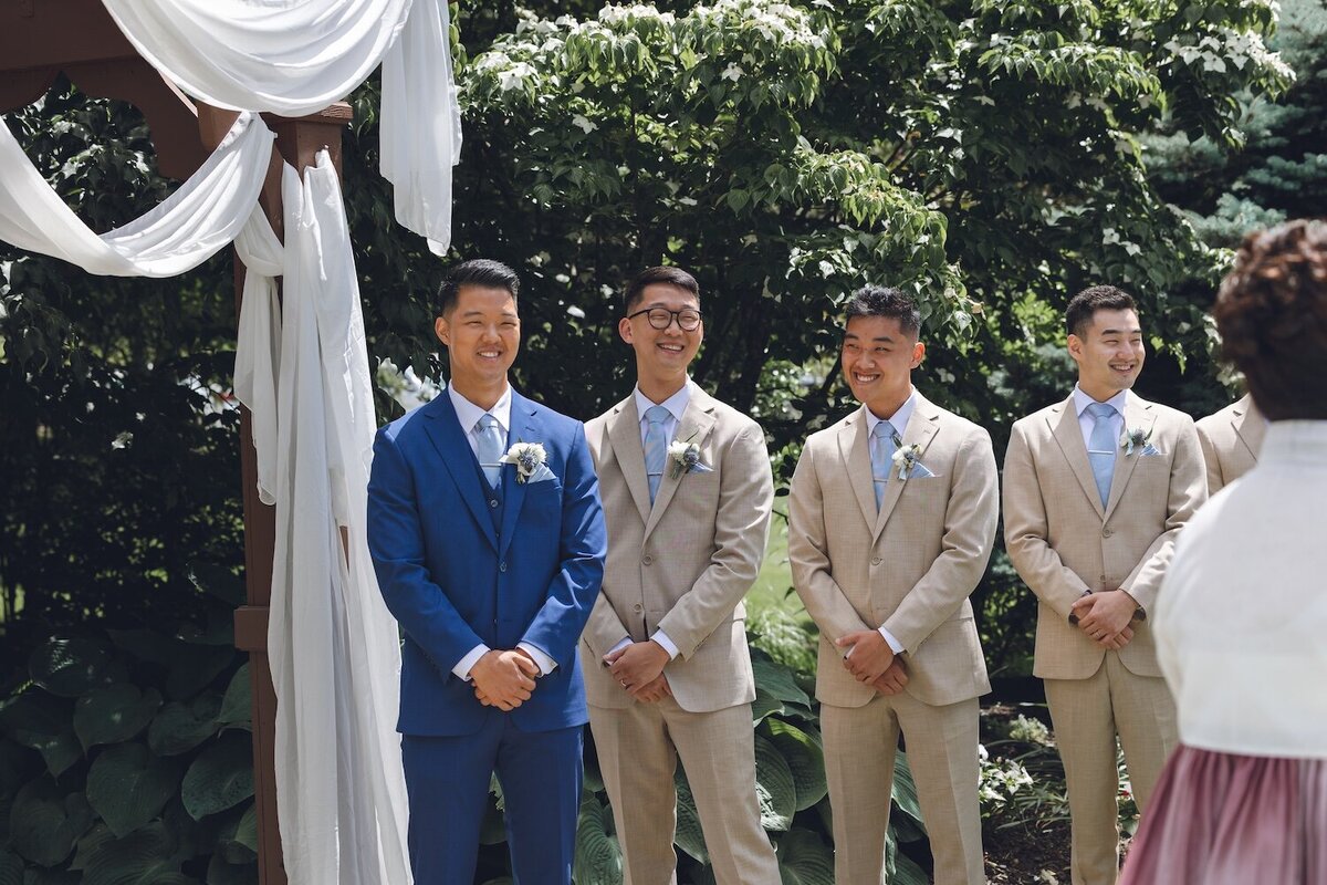 Groomsmen standing at floral altar during wedding ceremony