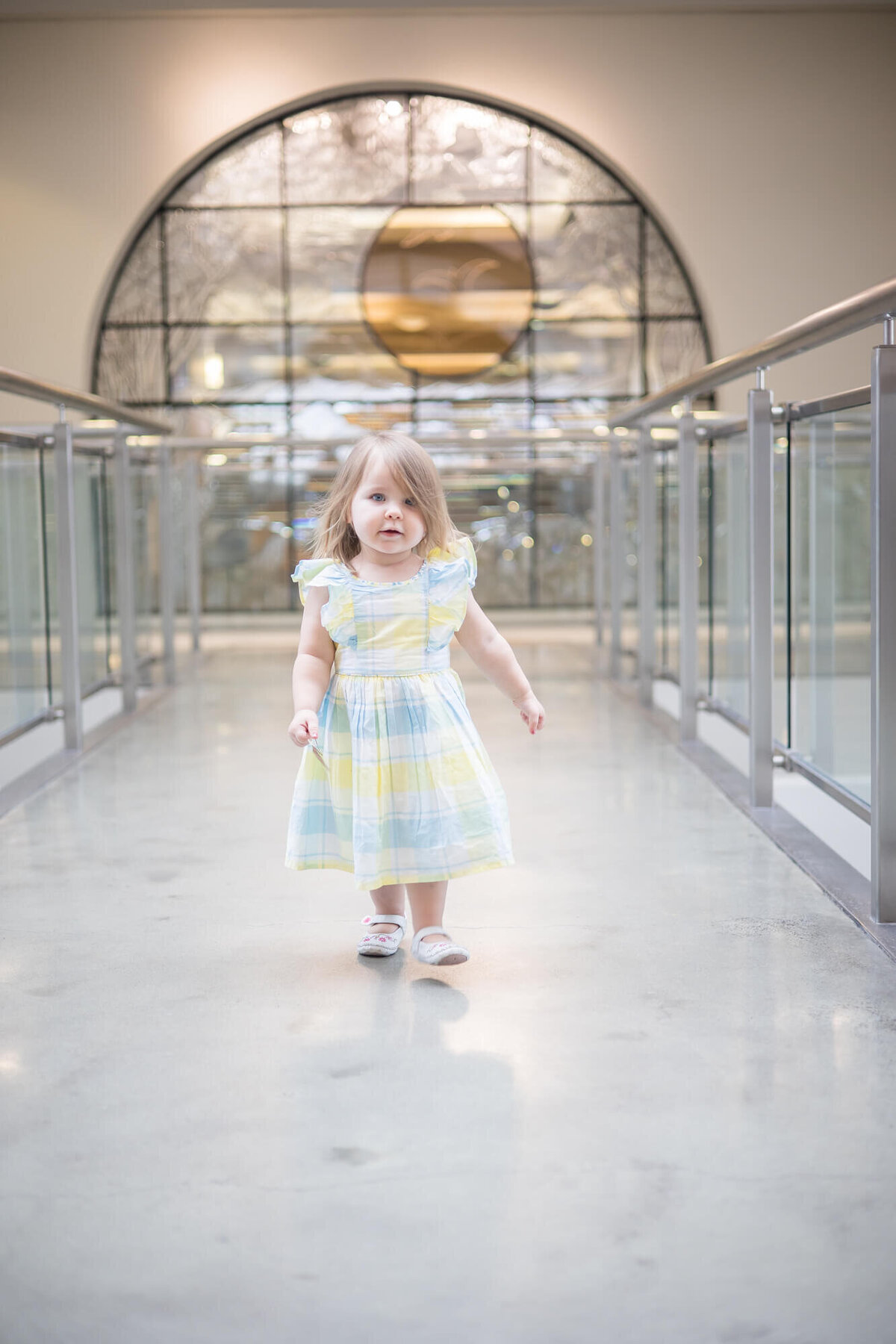 toddler girl in dress walking on an indoor bridge