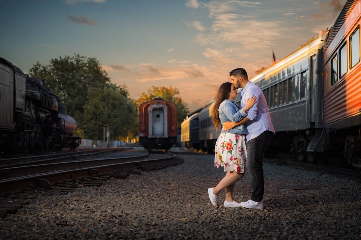Engaged couple kiss in front of a train station in old town sacramento.