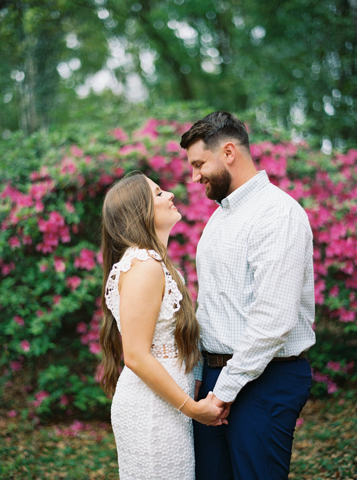 A romantic moment with a couple surrounded by vibrant azaleas in bloom at Jungle Gardens, beautifully captured on film by Morgan Alysse, Louisiana film photographer.