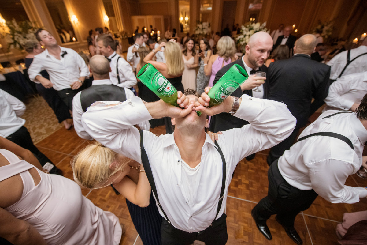 groom drinking two beers at the same during wedding reception party at The Muttontown Club