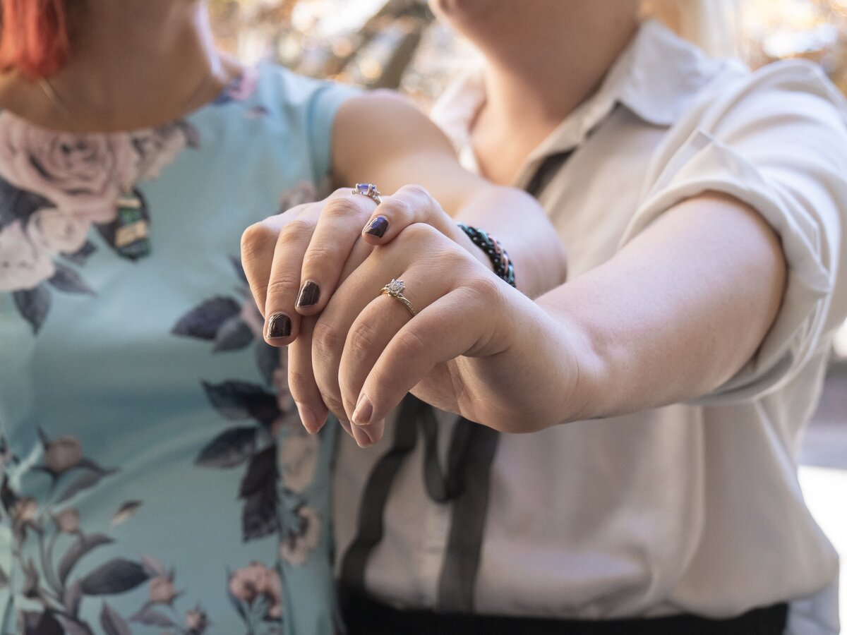 close up of engagement rings on two feminine hands at a queer engagement photos session