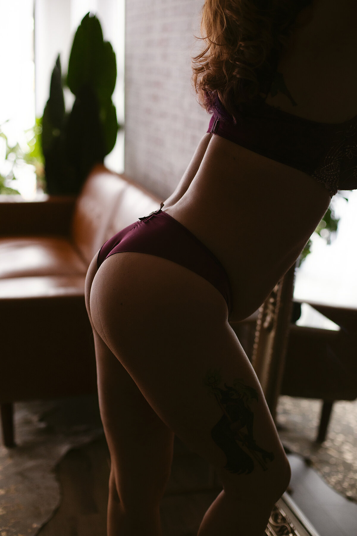 A woman in lingerie poses leaning  her backside out for a boudoir photoshoot.