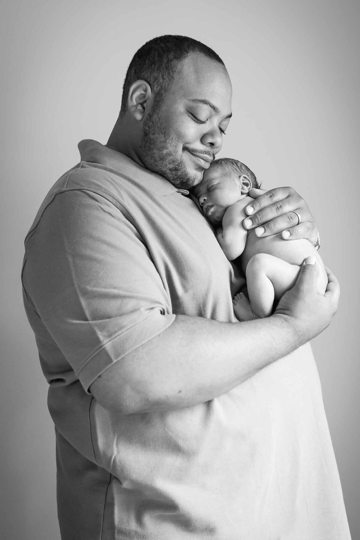 Black and white image of dad holding newborn son on his chest in Columbia, SC