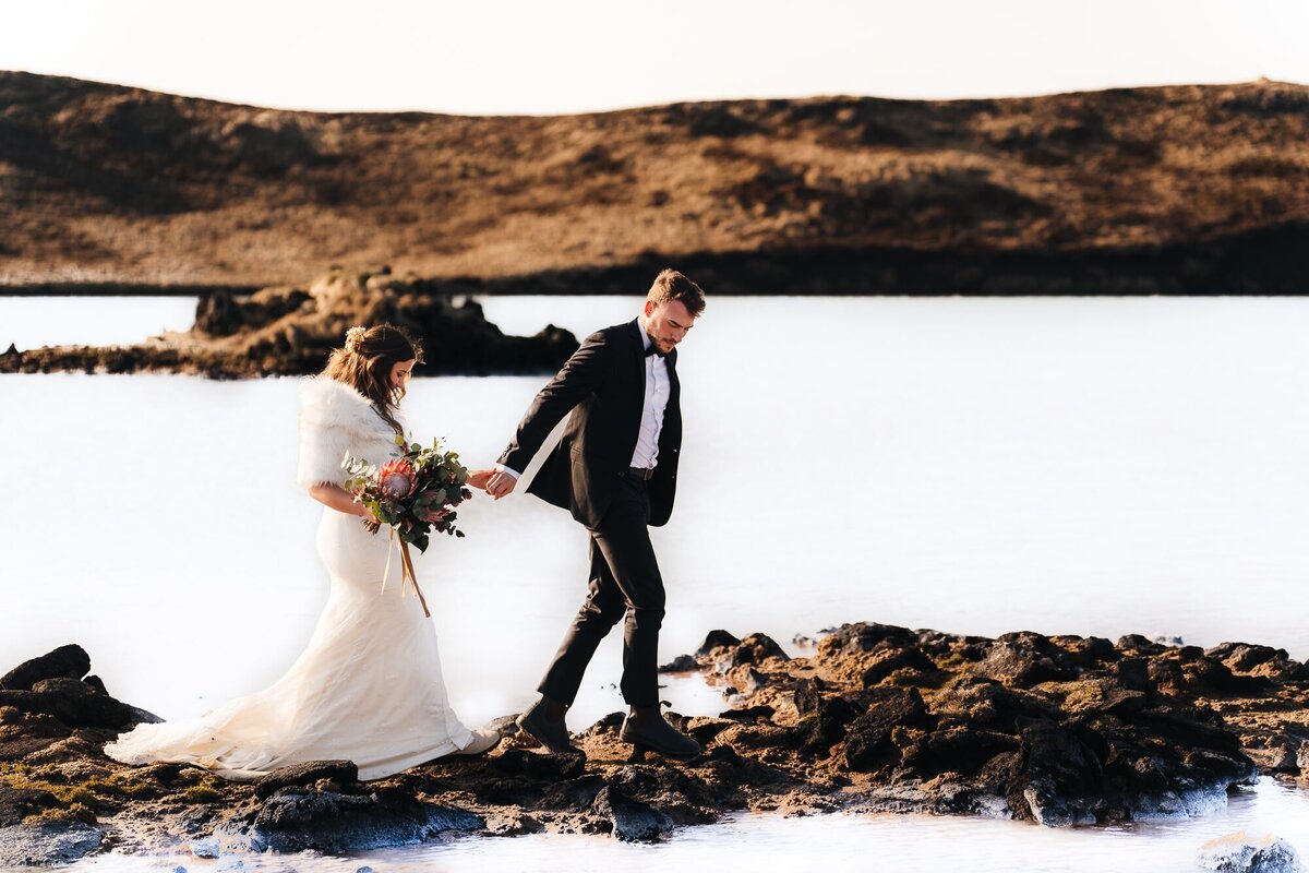 Hand in hand, the couple strolls through the enchanting Blue Lagoon in Iceland, creating a picturesque scene for their elopement journey.