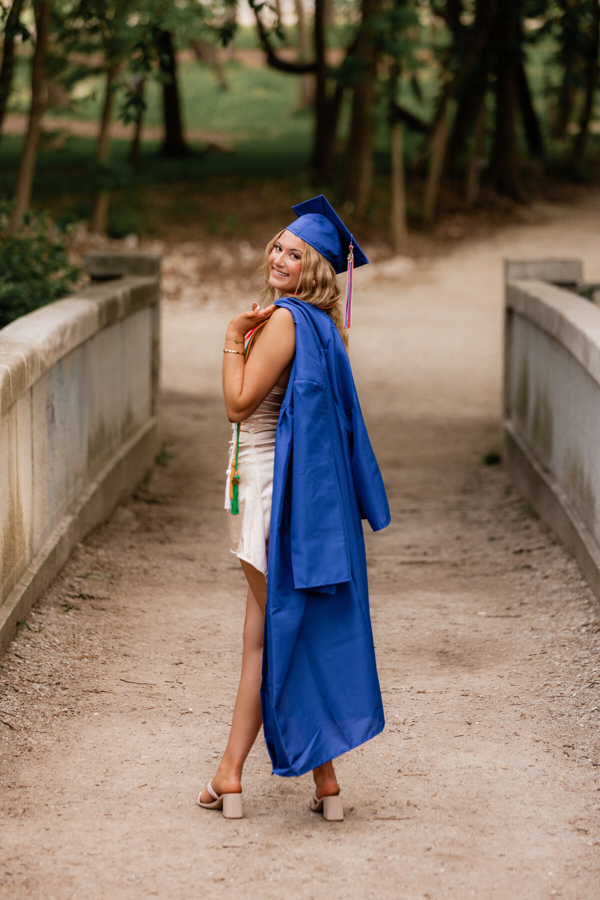 A graduate poses in her cap and gown for senior photos.