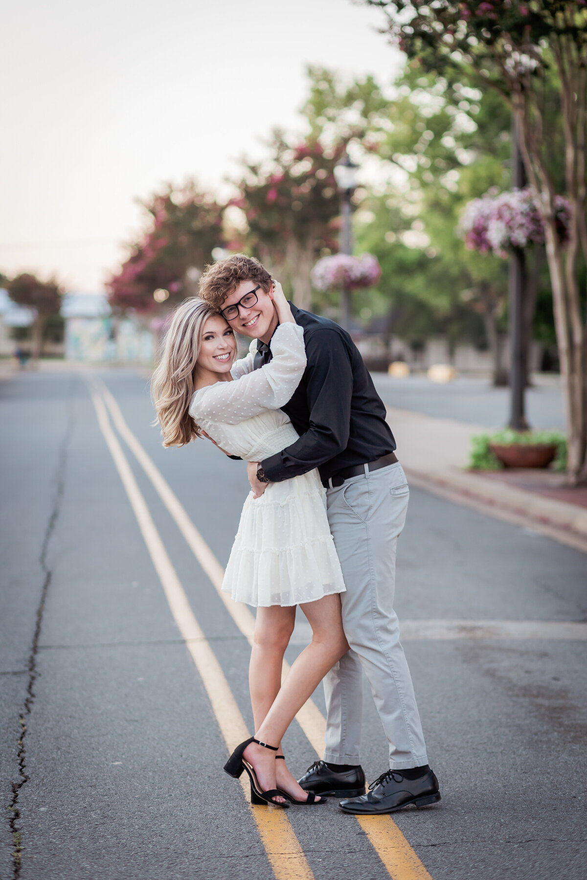 An engaged couple stands in the middle of the street while embracing each other. Captured by Arkansas Wedding Photographer, Photography by Karla.