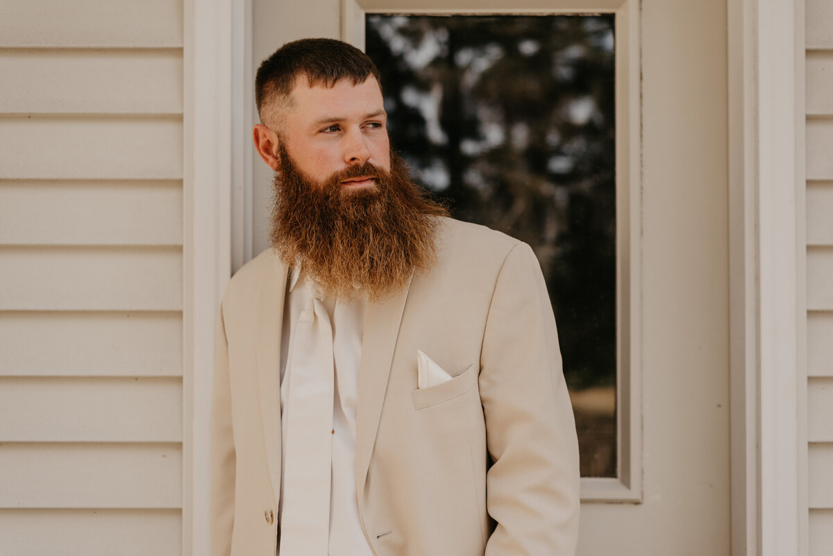Groom's formal portrait wearing a neutral, cream and beige suit for wedding.