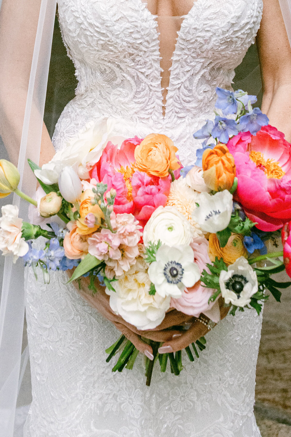 A wedding day portrait of the bride in her white wedding dress holding her colorful floral bouquet