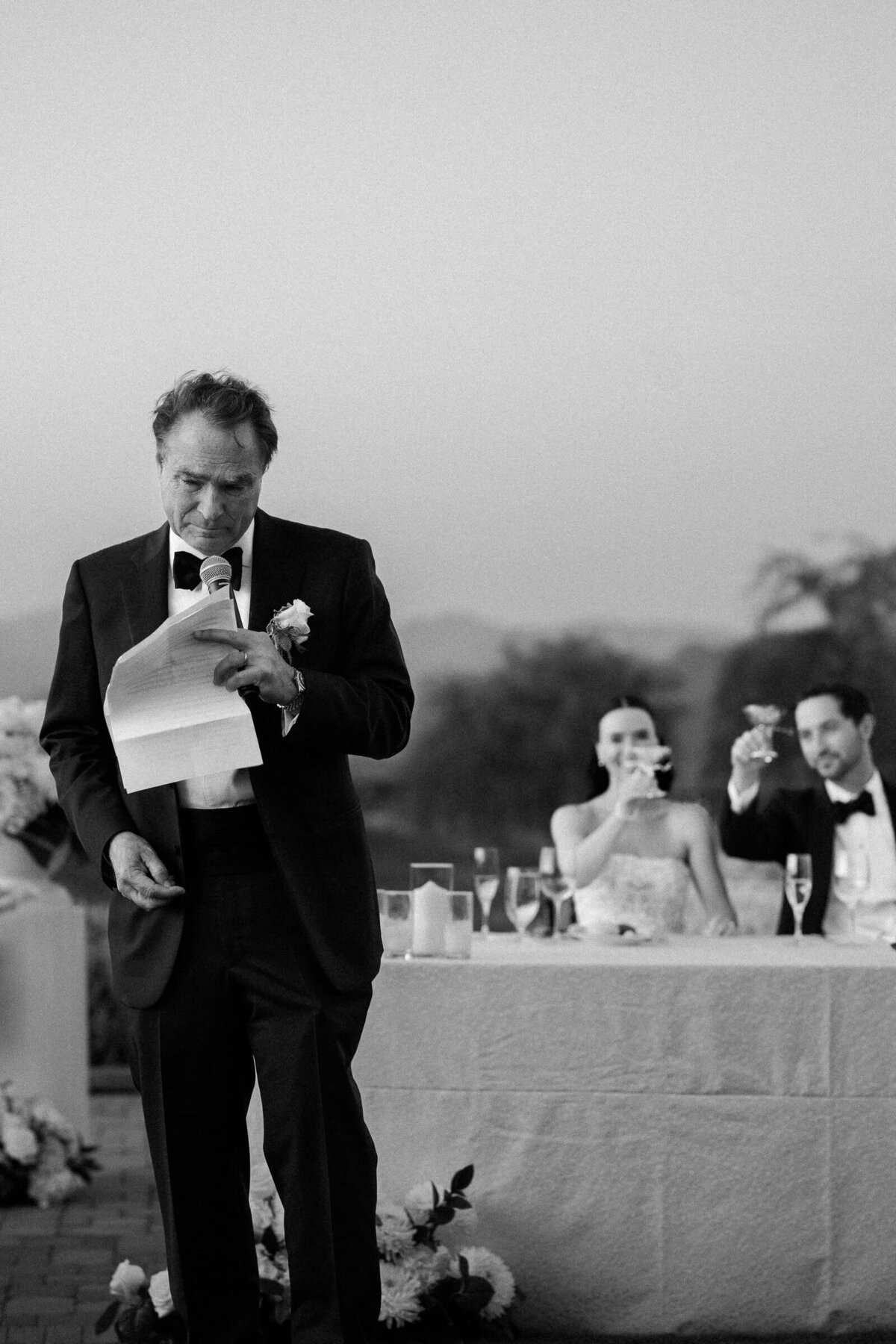 Father giving an emotional wedding toast as guests raise their glasses, beautifully captured by Arizona wedding photographers at sunset.