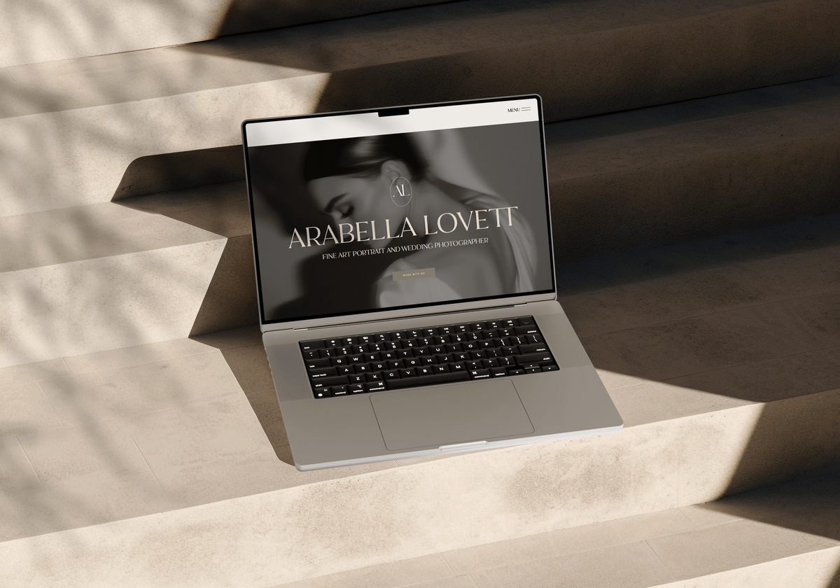 laptop open on stairs with photographers website 
