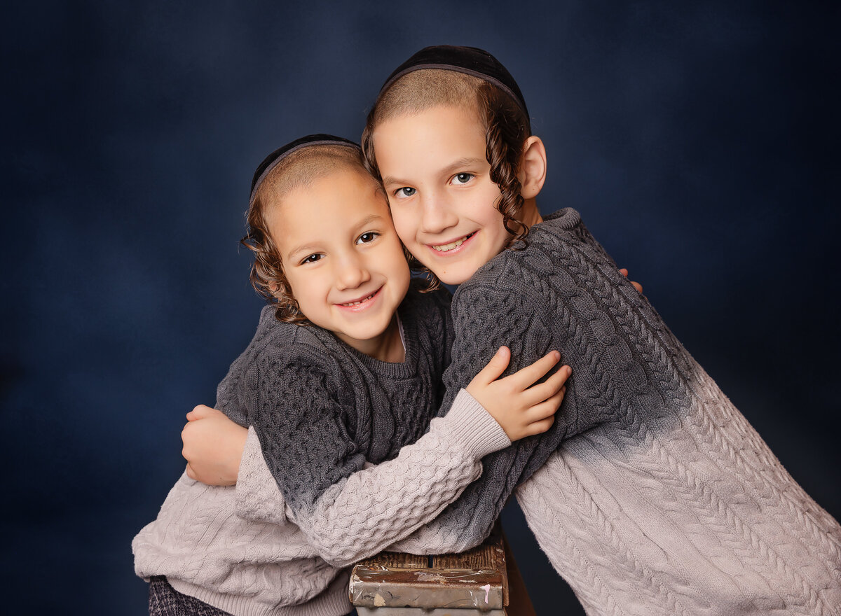 Two borthers hug and smile at the camera for a brooklyn family portrait. Captured by Brooklyn family photographer Chaya Bornstein