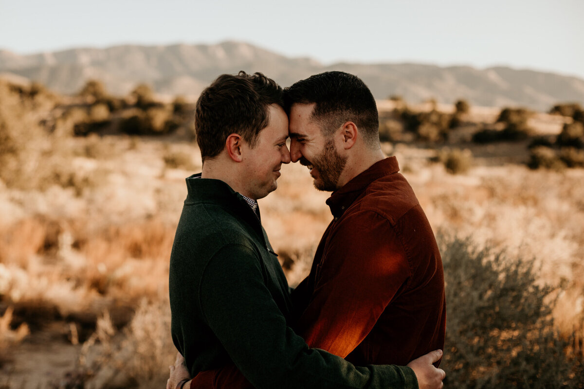 same sex couple holding each other looking into each others eyes with foreheads together