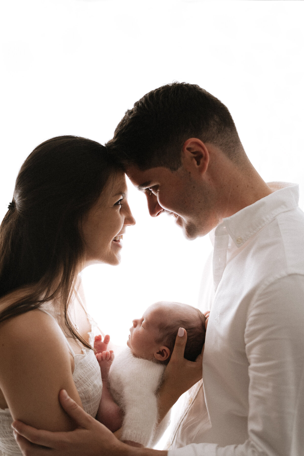 Parents holding newborn baby and smiling at newborn photoshoot in Billingshurst