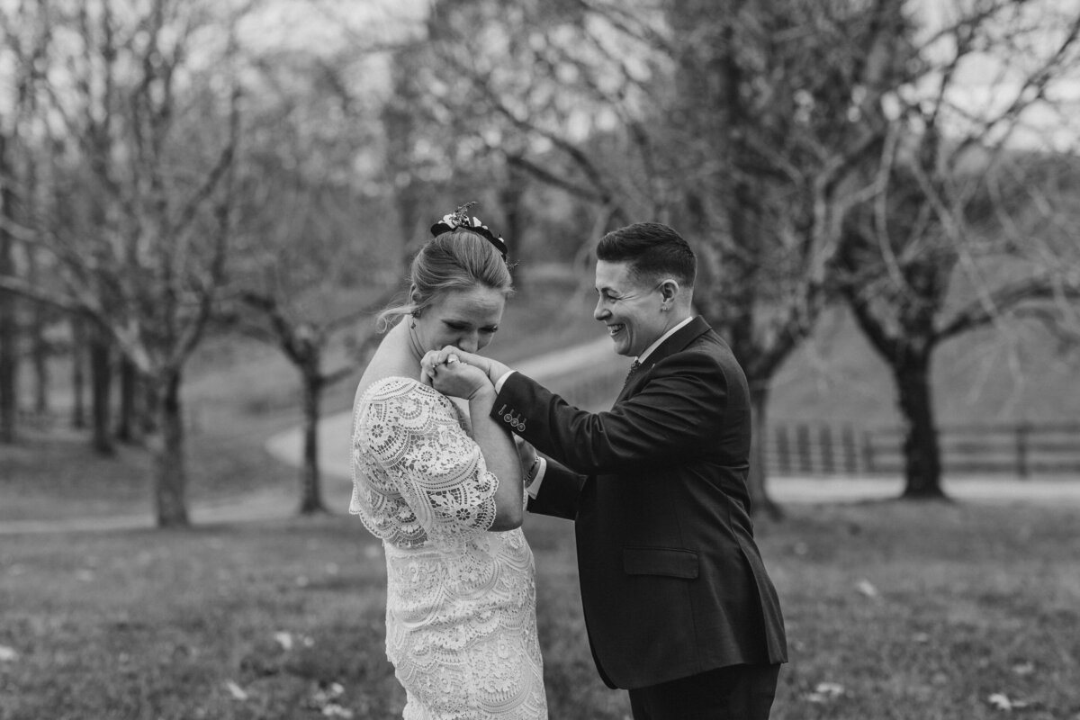A couple holding hands while one kisses the other's hand 