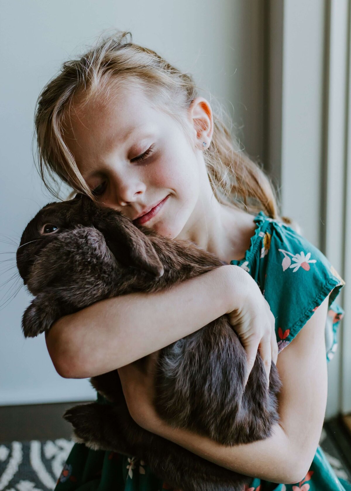 A little girl tenderly embracing a brown bunny captured by a Pittsburgh family photographer.