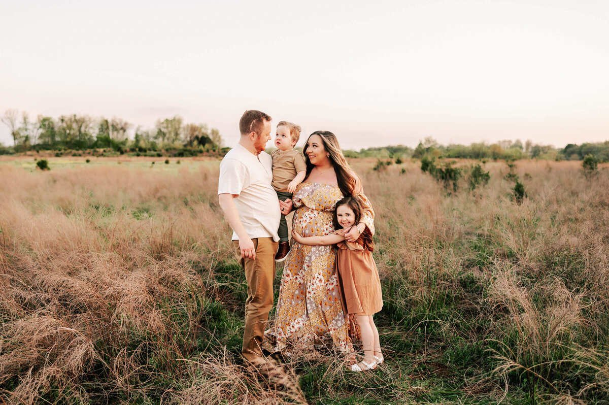 Springfield MO family photographer captures family hugging at sunset looking at dad