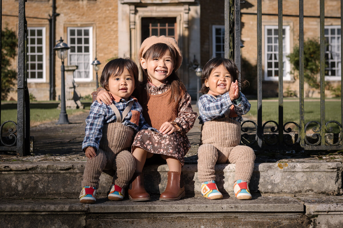 Big sister and her twin brothers sitting on the steps at Hinwick Hall Bedfordshire1