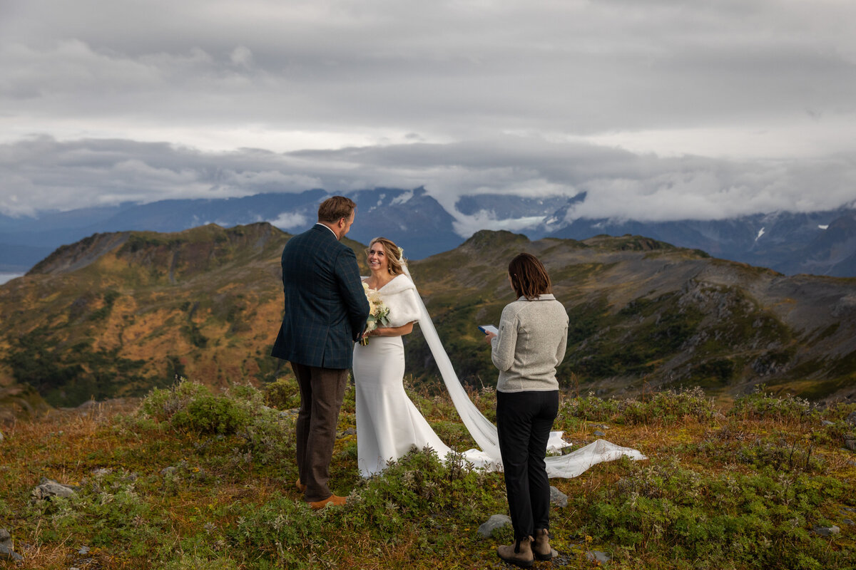 An officiant stands in front of the couple reading during their elopement ceremony in Alaska.