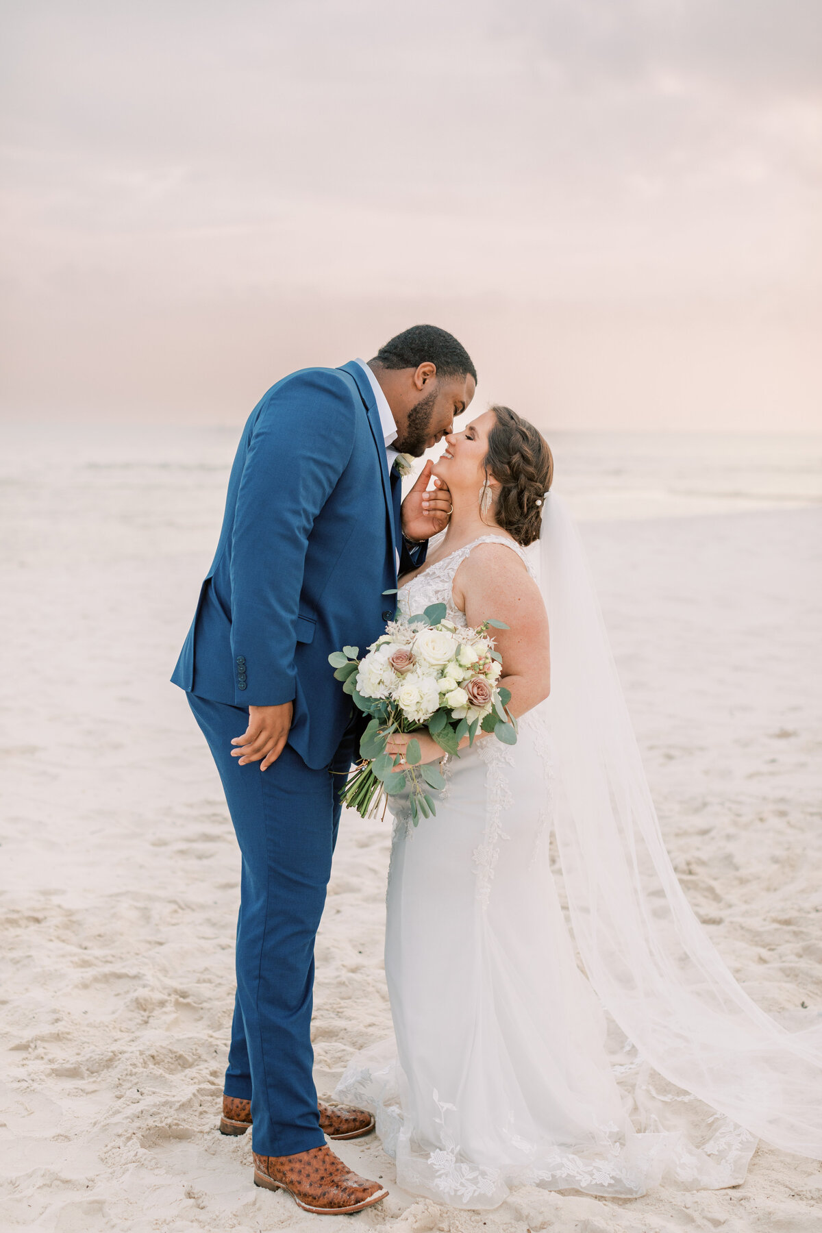 A couple kisses on the beach.