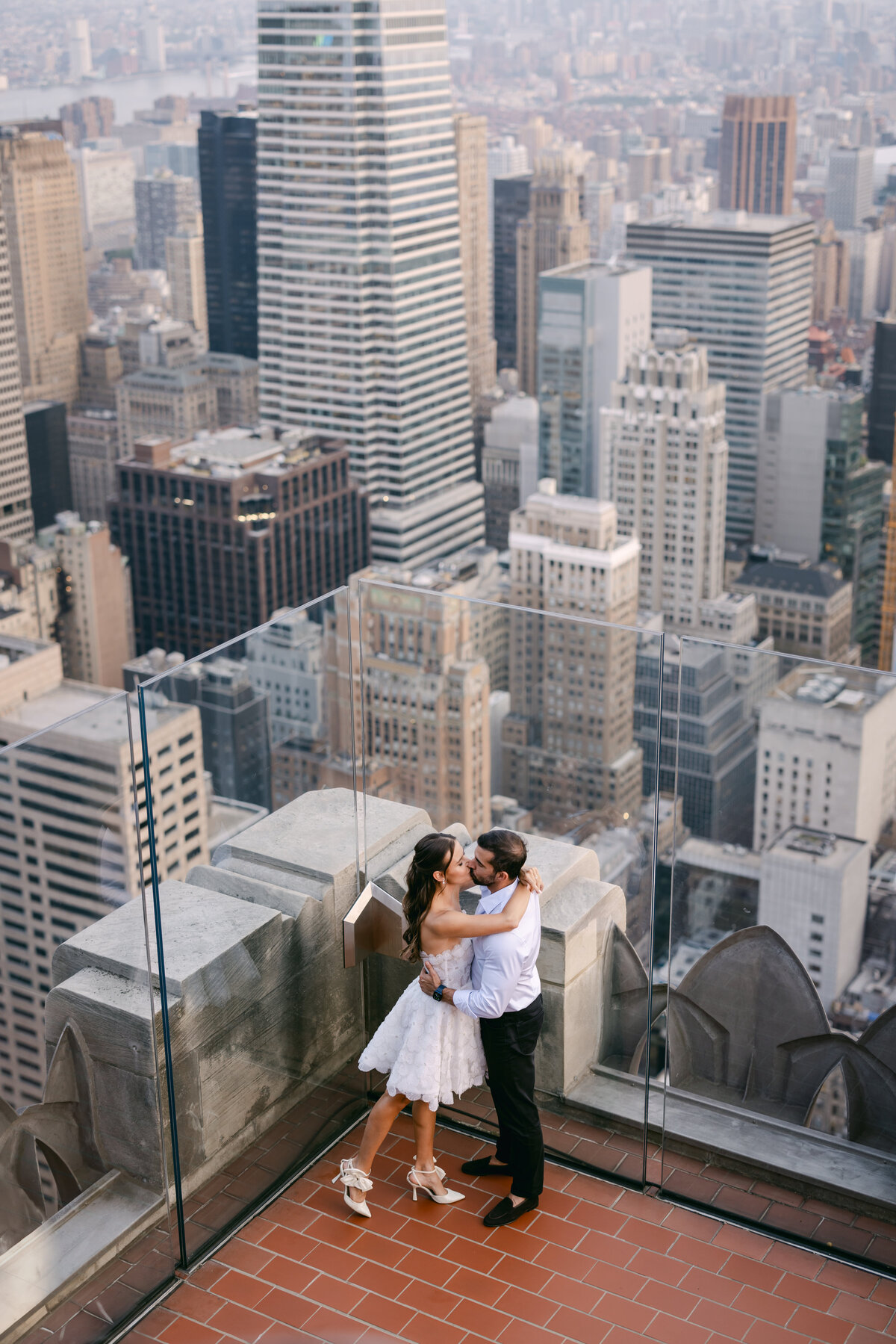 Capturing the beauty of love and the New York City skyline, a bride and groom share a moment on the Top of the Rock at Rockefeller Center.
