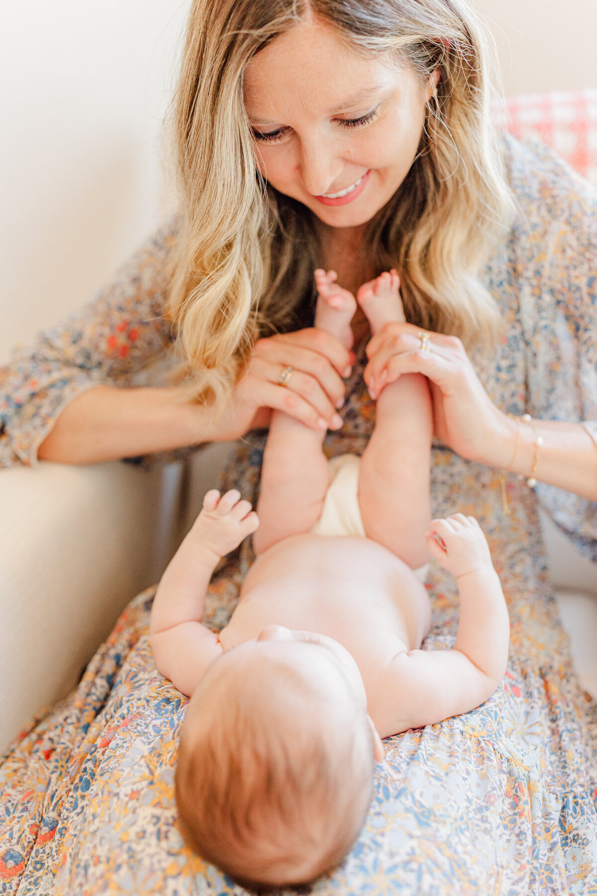 Mother smiles at her baby in her lap at a session by Boston Newborn Photographer H. MacLean Photography