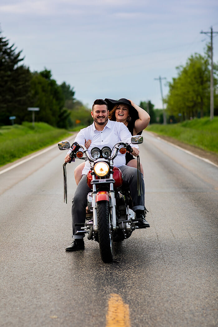 man-drives-motercycle-woman-hangs-on-to-hat