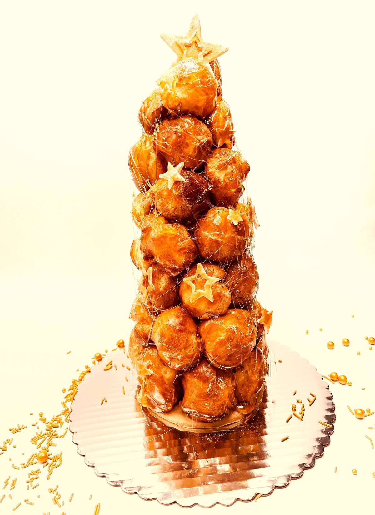 Spun sugar decorated croquembouche accented with chocolate stars. Filled with vanilla pastry cream and dipped in caramel