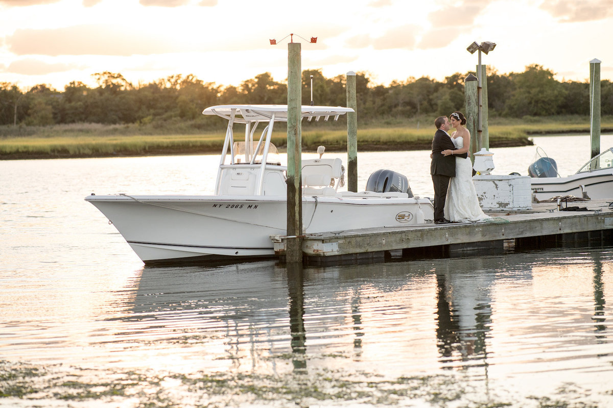 photo of bride and groom on the dock in front of boat from wedding reception at Lawrence Yacht and Country Club
