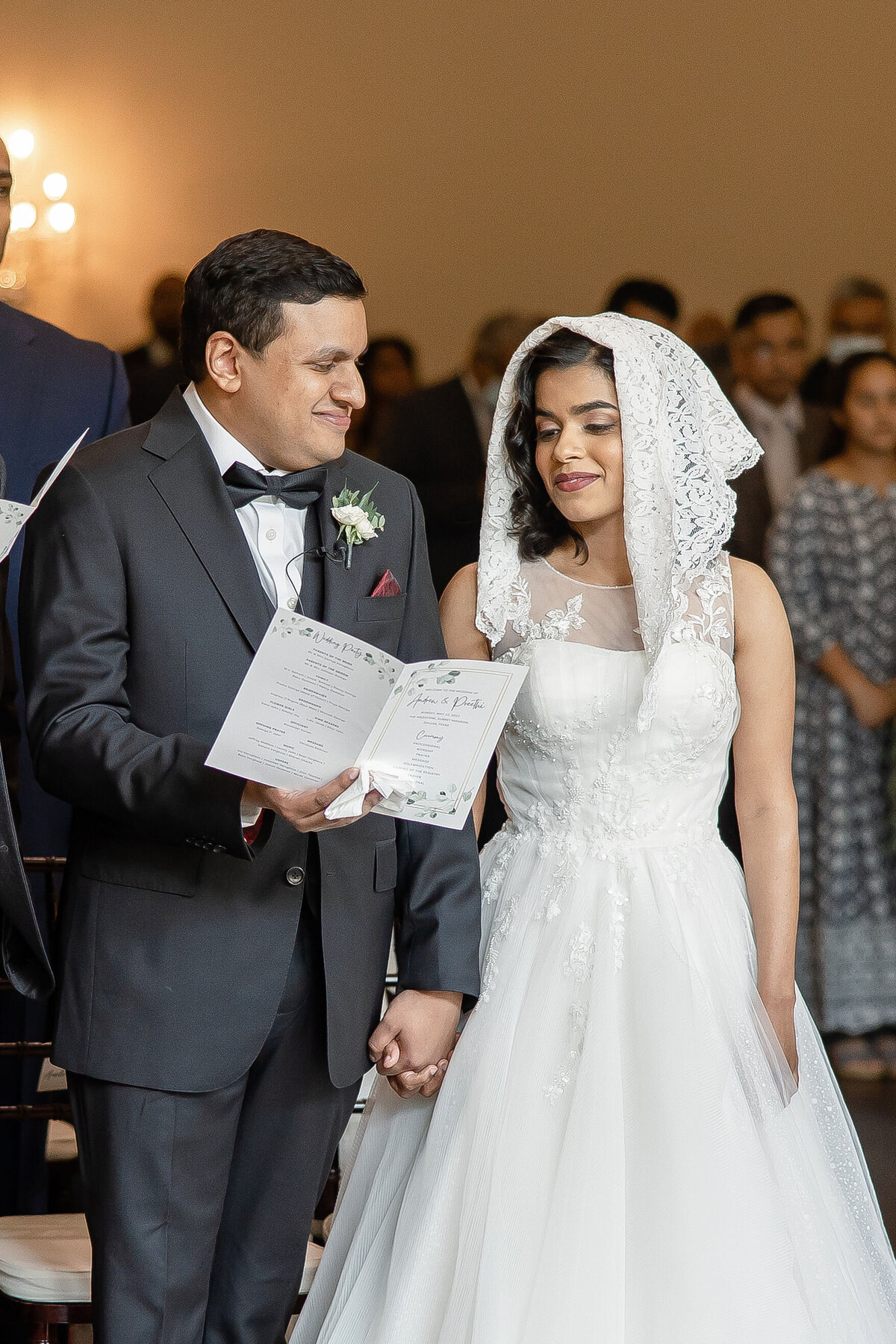 bride with white scarf on head sings with groom holding program at Aubrey Mansion wedding