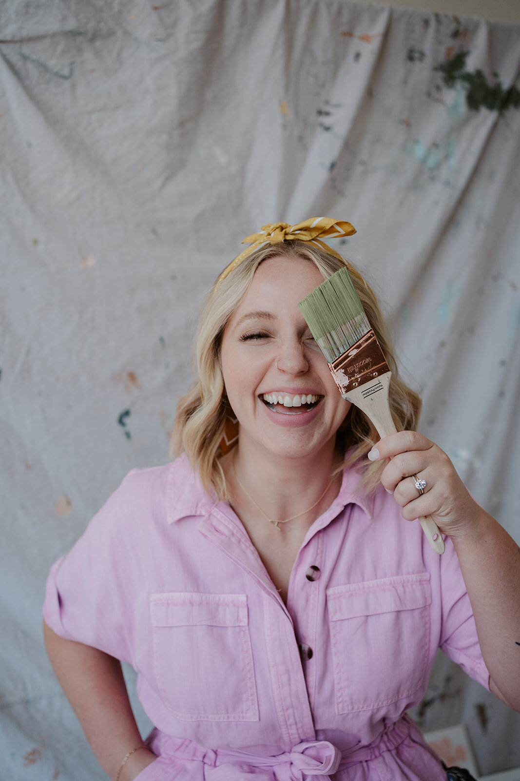 Portrait of an artist laughing while holding a paintbrush during a Wildher and Co creative branding session.