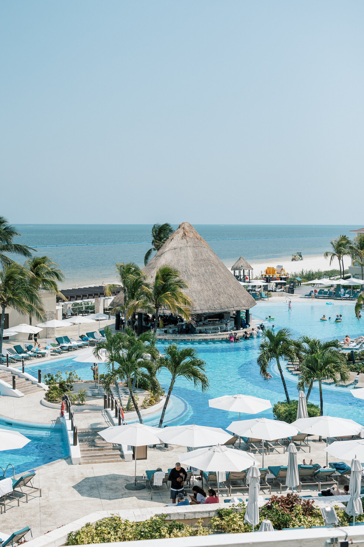 Cancun resort pool scene with palm trees and cabana bar, shot by a Philadelphia wedding photographer at a destination wedding.
