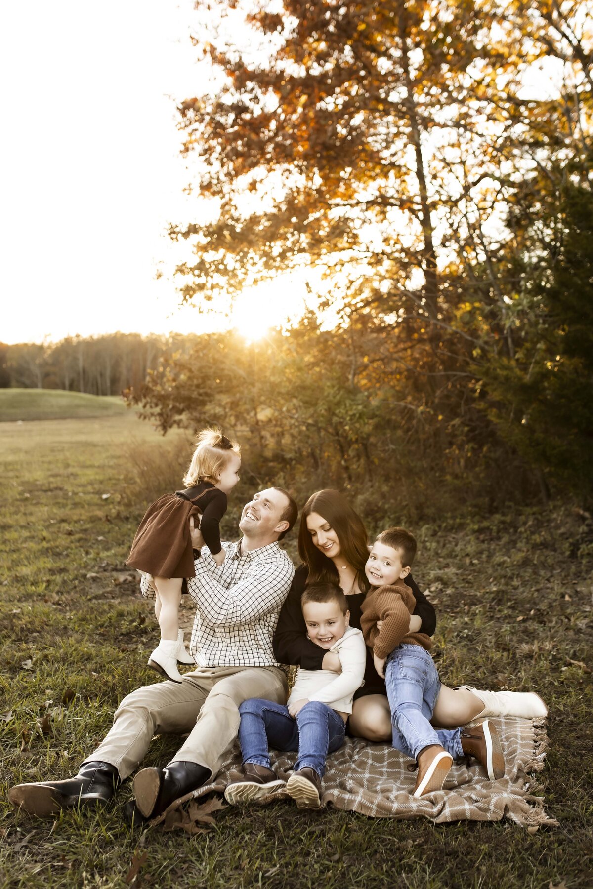 Family cuddled up on blanket during golden hour on a Missouri fall day