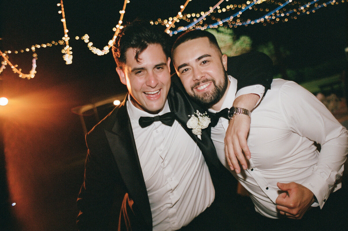 Groom and best man sharing a joyful moment on the dancefloor, captured in a documentary wedding photography style — Carmel wedding photography by Kate Winters Photography.