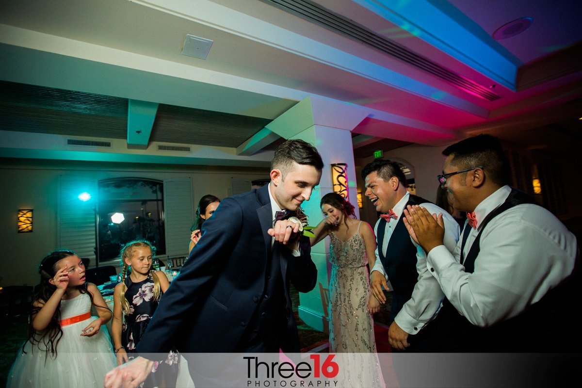 Groom dances in the middle of friends at wedding reception