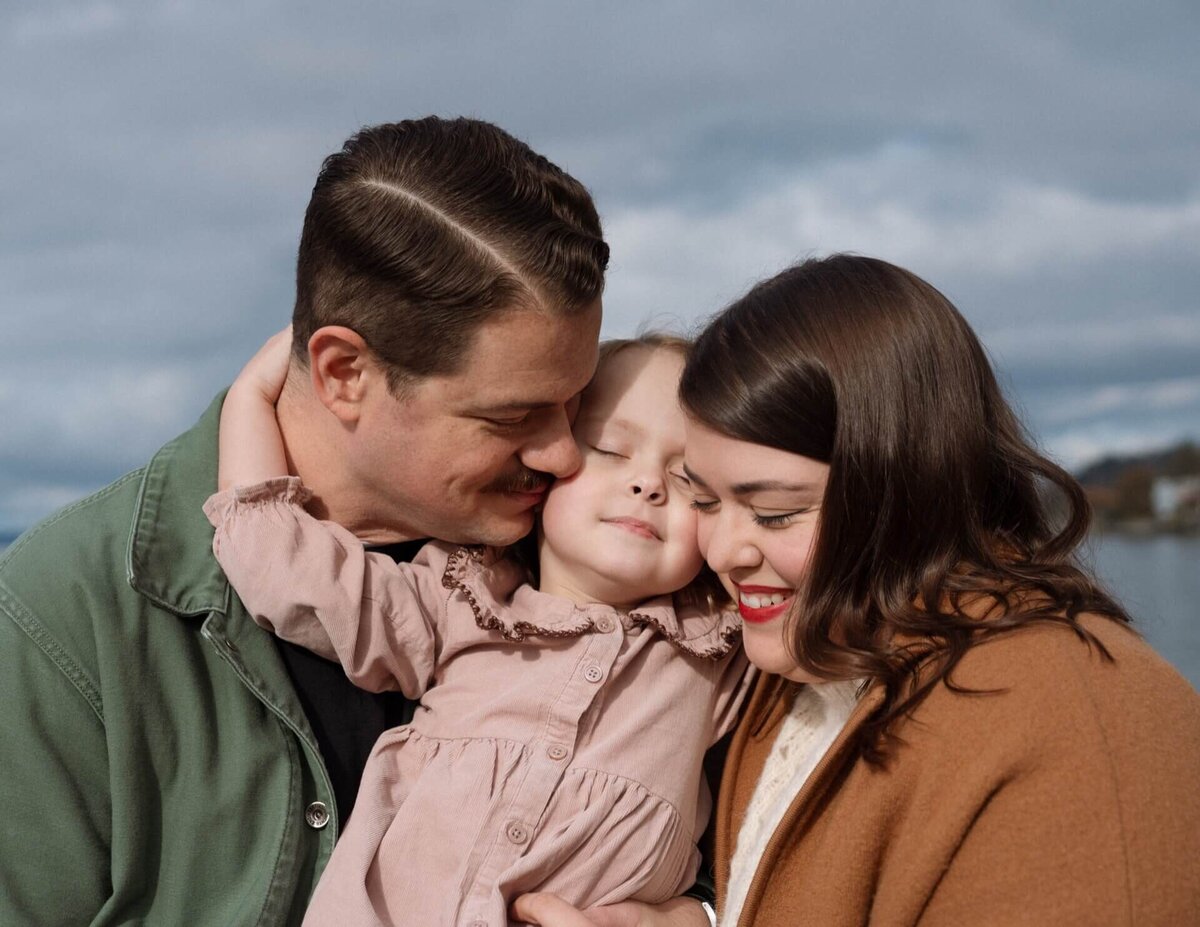 mom and dad hugging little girl wearing pink