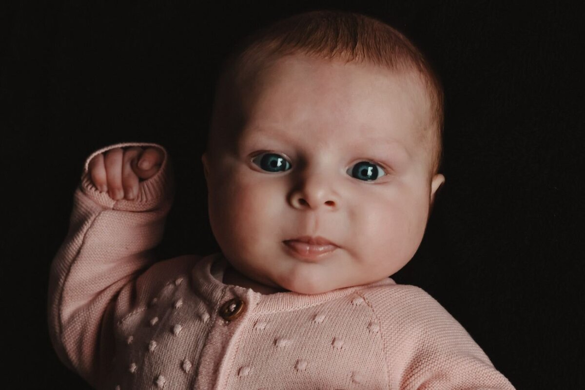 Detailfoto van het gezichtje van een pasgeboren baby, met de focus op de ogen en de zachte huid